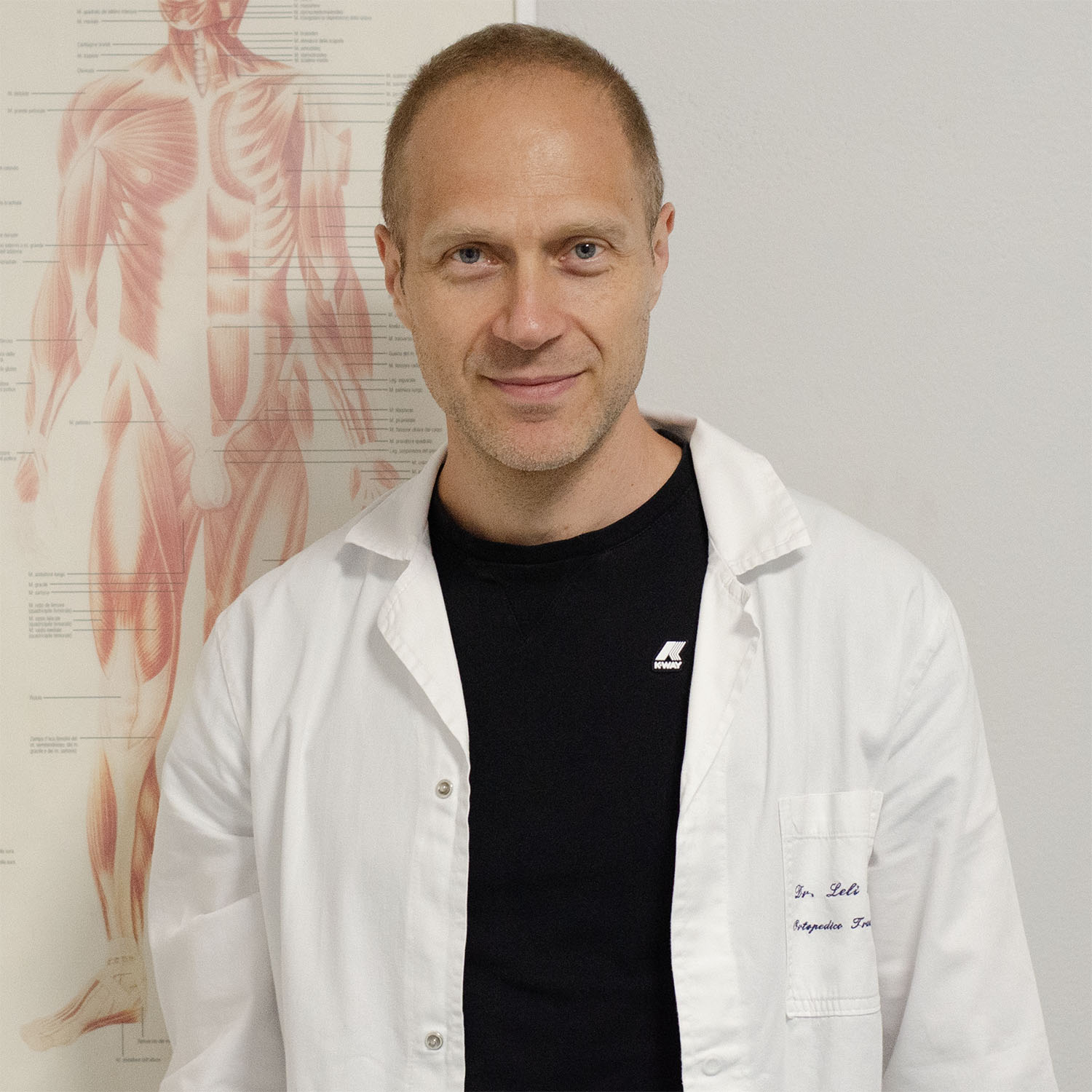 dottor andrea leli a fianco di un poster dove è rappresentato il sistema muscolare umano